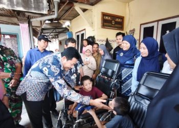 Bupati Sidoarjo, Subandi, saat menyerahkan bantuan kursi roda pada Arafah dan Arafih, warga Desa Banjarbendo.