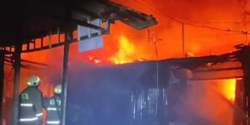 Petugas berusaha memadamkan api saat kebakaran tiga warung di Desa Wage Sidoarjo.