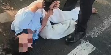 Petugas patroli Polresta Sidoarjo, saat berupaya membujuk dan meminta perempuan yang tengah menangis dan berguling di aspal jalan untuk menepi ke tempat yang lebih aman.