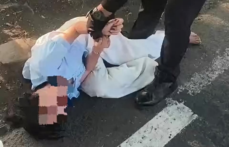 Petugas patroli Polresta Sidoarjo, saat berupaya membujuk dan meminta perempuan yang tengah menangis dan berguling di aspal jalan untuk menepi ke tempat yang lebih aman.